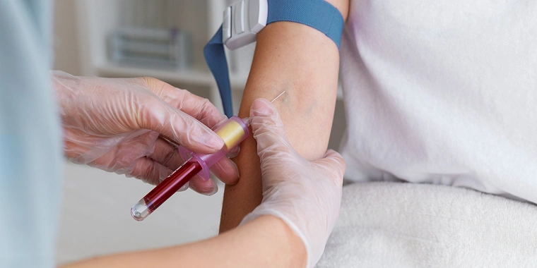 Nurse drawing blood from a patient’s arm.